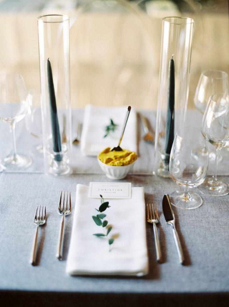 Minted placecards, grey tapered candles on grey wedding linen with ghost chairs and loose green and white floral arrangements by Blooms and Flora at Alton Mill Wedding | Goldie Mill Wedding | Caledon Wedding Photographer | Guelph Wedding Photographer | Kayla Yestal